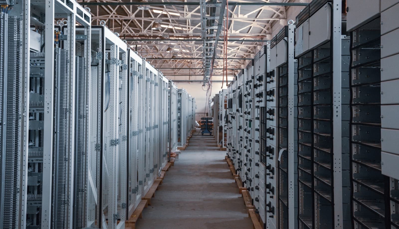 An aisle between rows of grey electrical equipment cabinets